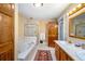 A well-lit bathroom featuring a jacuzzi tub, a walk-in shower, and double sinks with tile countertops at 433 N Ogden St, Denver, CO 80218