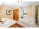 Bright bathroom featuring a whirlpool tub, tiled walls, and double sinks with gold fixtures at 433 N Ogden St, Denver, CO 80218