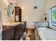 Bathroom with dual sinks, dark cabinets, and soaking tub with tile surround at 845 Urban St, Lakewood, CO 80401