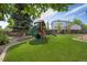 Fenced backyard with lush green grass, mature trees, and fun playset with slide and swings at 12513 Alcott St, Broomfield, CO 80020