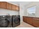 Well-lit laundry room with side-by-side washer and dryer, cabinets, and a window at 14620 Prairie Sky Ln, Broomfield, CO 80023