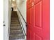 Entryway with a bright red door, ascending carpeted stairs, and a black railing, creating a welcoming atmosphere at 8751 Pearl St # J3, Thornton, CO 80229