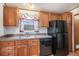 Efficient kitchen featuring classic wood cabinets, a black dishwasher and refrigerator at 1683 Monroe St, Strasburg, CO 80136