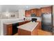 Cozy kitchen features an island, wood cabinetry, black appliances and wood flooring at 157 Sand Cherry St, Brighton, CO 80601