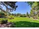 Expansive backyard featuring lush green grass and professionally landscaped gardens, perfect for outdoor activities at 5 Walden Ln, Cherry Hills Village, CO 80121