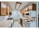 Kitchen featuring wood cabinets, white appliances, and tile flooring at 17381 E Mansfield Ave # 711L, Aurora, CO 80013