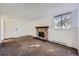A spacious living room featuring a stone fireplace, neutral carpeting, and a bright window at 17381 E Mansfield Ave # 711L, Aurora, CO 80013