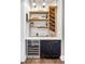 Charming home bar with black and white finishes, wood shelves, wine storage and beverage refrigerator at 17820 Queensmere Dr, Monument, CO 80132