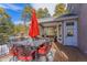 An outdoor deck with a dining area, covered seating, a patio umbrella, and views of mature trees at 17820 Queensmere Dr, Monument, CO 80132
