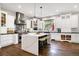 Bright and airy kitchen featuring an oversized island with marble counters, a stainless steel range hood, and hardwood floors at 17820 Queensmere Dr, Monument, CO 80132