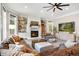 Inviting living room with a fireplace, comfortable seating, built-in shelves, and a large ceiling fan at 17820 Queensmere Dr, Monument, CO 80132
