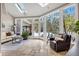 Bright sunroom featuring stone tile floor, a large bay window, skylights, a sofa and a leather chair at 17820 Queensmere Dr, Monument, CO 80132