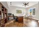 Bright home office featuring custom wood built-ins, hardwood floors, ample natural light, and a relaxing seating area at 17820 Queensmere Dr, Monument, CO 80132
