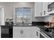 Modern kitchen featuring white cabinets, stainless steel appliances, black countertops, and wood-look flooring at 20908 E Dorado Cir, Centennial, CO 80015