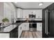 Modern kitchen featuring white cabinets, stainless steel appliances, black countertops, and wood-look flooring at 20908 E Dorado Cir, Centennial, CO 80015