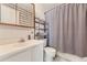 Bright bathroom with white cabinets, shower with gray patterned curtain, and organized shelving at 9958 Milwaukee St, Thornton, CO 80229