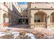 Exterior of a tan home with brick courtyard, covered entrances and manicured landscaping at 40 Madison St # 103, Denver, CO 80206