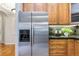 Kitchen area featuring stainless steel refrigerator, wood cabinets and stone countertops at 40 Madison St # 103, Denver, CO 80206