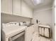Functional laundry room with modern washer and dryer, ample cabinet storage, and tile flooring at 7782 S Louthan St, Littleton, CO 80120