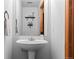 Pedestal sink in a half bathroom with a decorative mirror and a small floating shelf at 2430 E 109Th Dr, Northglenn, CO 80233