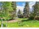Landscaped backyard featuring lush greenery, mature trees, and a well-maintained lawn at 12046 W Green Mountain Dr, Lakewood, CO 80228