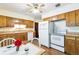 Bright kitchen with wooden cabinets, white appliances, and a breakfast table with white chairs at 12046 W Green Mountain Dr, Lakewood, CO 80228