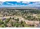 Scenic aerial view showcasing a community surrounded by trees and mountains in the distance under a cloudy blue sky at 8687 N Pinery Pkwy, Parker, CO 80134