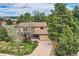 Aerial view of a charming house with a tile roof, surrounded by lush greenery and mature trees on a sunny day at 8687 N Pinery Pkwy, Parker, CO 80134
