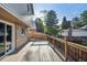 Spacious wooden deck perfect for outdoor entertaining with wooden railing and a view of the treed backyard at 10909 W 65Th Way, Arvada, CO 80004