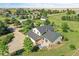 Aerial view showcasing a charming two-story home with a deck and an expansive driveway, surrounded by mature trees at 2882 Gentry Ct, Watkins, CO 80137