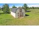 Aerial view of barn style shed with wooden doors, white siding, and expansive grassy yard at 2882 Gentry Ct, Watkins, CO 80137