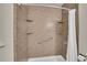 Shower featuring a built-in corner shelves, grab bar, and a marble-style wall surround at 2882 Gentry Ct, Watkins, CO 80137