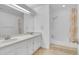 Bright bathroom featuring a double vanity, a large mirror, and a tub with shower at 11247 Wyandot St, Denver, CO 80234