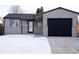 Updated Ranch home with a modern black garage door and snow-covered front yard at 16930 E Wagontrail Pkwy, Aurora, CO 80015