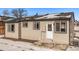 Tan house exterior with white door, dark window frames, and small patio at 16930 E Wagontrail Pkwy, Aurora, CO 80015