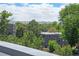 Exterior view of a modern apartment complex, partially obscured by mature trees with a mountain view in the background at 2726 Federal Blvd # 1, Denver, CO 80211