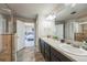 Bathroom with double sinks, dark wood cabinetry, and a shower with glass doors, leading to the bedroom at 16737 Lake Helen Blvd, Mead, CO 80542