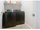 A laundry room featuring a modern, front-loading, Samsung washer and dryer with tiled floor and shelf at 16737 Lake Helen Blvd, Mead, CO 80542