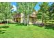Spacious backyard featuring a two-story house, lush green lawn, and beautiful birch trees at 19235 Wakonda Way, Monument, CO 80132