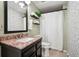 Basement bathroom with granite vanity, shower/tub combo, and patterned wallpaper at 9189 Fallen Rock Rd, Conifer, CO 80433