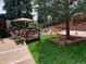 Spacious backyard with wood deck, dining area, waterfall feature, and mature trees at 975 S Queen Way, Lakewood, CO 80226
