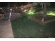 Night view of a serene backyard with a deck and lush lawn illuminated by landscape lighting at 975 S Queen Way, Lakewood, CO 80226