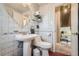 Well-lit bathroom with pedestal sink, toilet, and decorative wall tiles at 975 S Queen Way, Lakewood, CO 80226