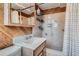 Rustic bathroom with wood paneling, functional storage, and a shower featuring floral-patterned tiles at 975 S Queen Way, Lakewood, CO 80226