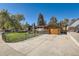 View of the home highlighting the attached garage, brick accents, and well-manicured front yard with black iron fence at 975 S Queen Way, Lakewood, CO 80226