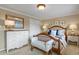 Bedroom with an upholstered bench at the foot of the bed, dresser, mirror, and neutral wall color at 4510 E 121St Pl, Thornton, CO 80241