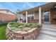 Inviting front porch with brick accents, decorative stone retaining wall, and charming landscaping at 4510 E 121St Pl, Thornton, CO 80241