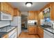 Efficient kitchen with wood cabinets, white appliances, and adjacent dining area at 4510 E 121St Pl, Thornton, CO 80241