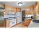 Efficient kitchen featuring wood cabinets, white appliances, and grey countertops at 4510 E 121St Pl, Thornton, CO 80241