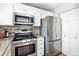 Well-equipped kitchen featuring stainless steel appliances, white cabinets, and tiled backsplash at 6401 S Forest St, Centennial, CO 80121